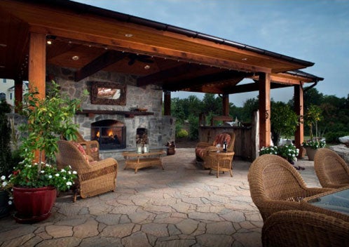 Elegant outdoor patio with stone fireplace, wooden pergola, and cozy seating.