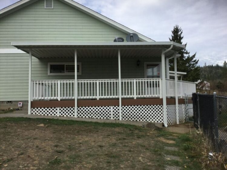 Covered patio area with white railing, enhancing outdoor space of a home