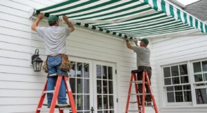 Workers installing manual retractable patio cover on white house exterior